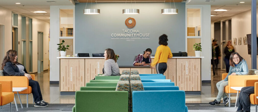 The main lobby of the Tacoma Community House building with colorful chairs and people sitting, standing, or talking.