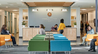 The main lobby of the Tacoma Community House building with colorful chairs and people sitting, standing, or talking.